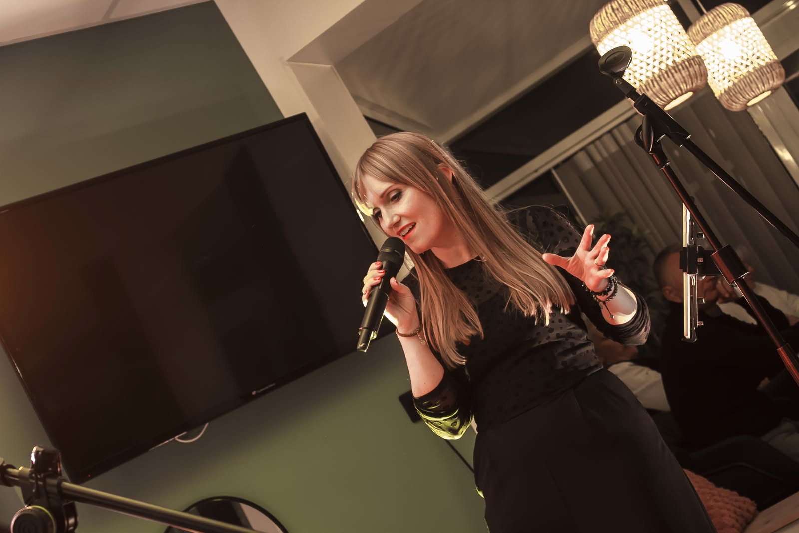 Symbiose en concert en 2026, Angélique chante au micro dans une ambiance chaleureuse