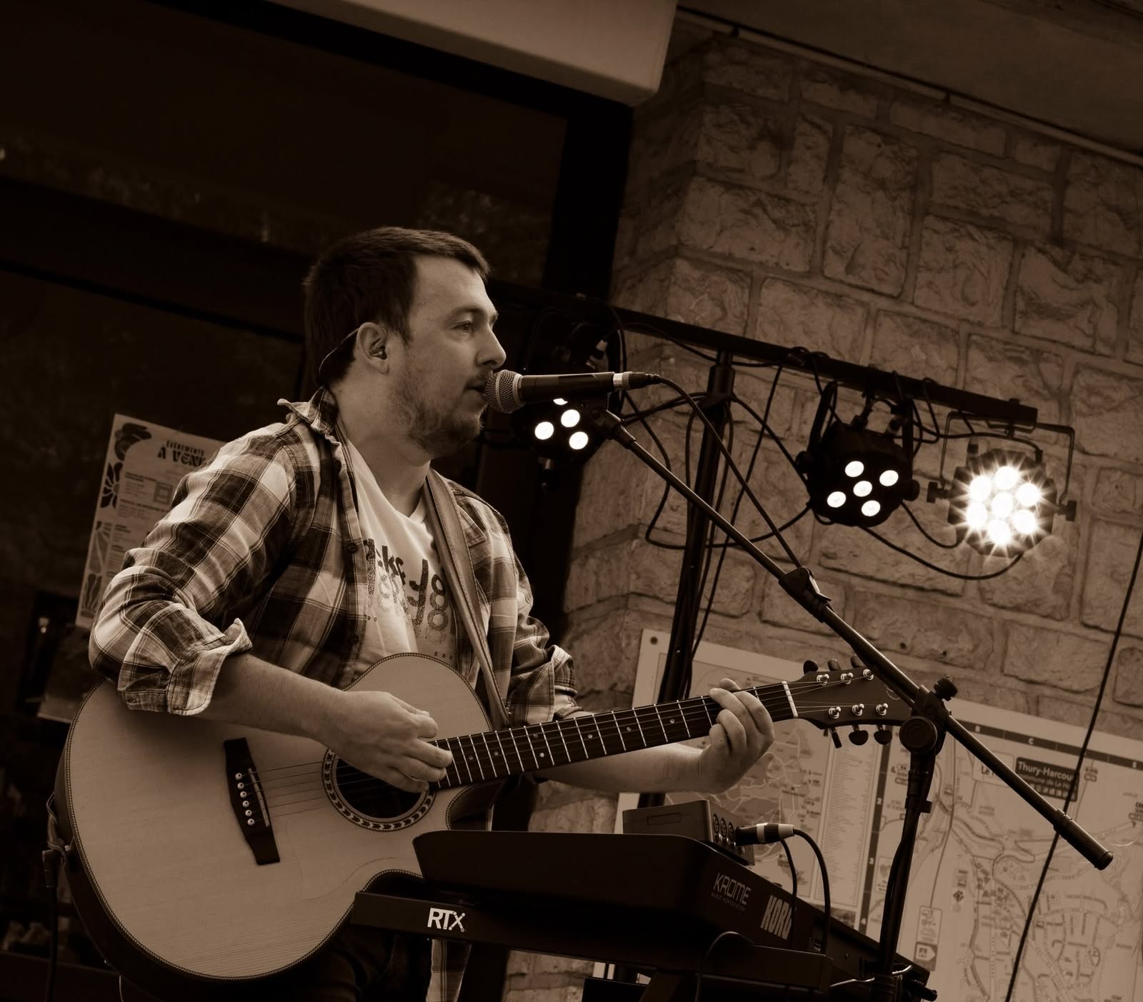 Symbiose en concert en 2026, Alex chante et joue de la guitare acoustique lors d'un concert live